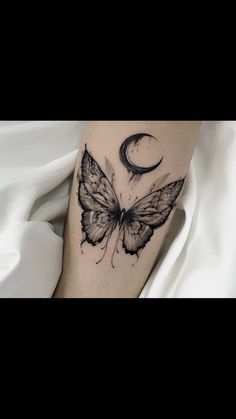 a black and white photo of a butterfly with a crescent moon tattoo on the leg