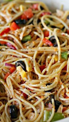 pasta with olives, peppers and chicken in a white bowl on a wooden table