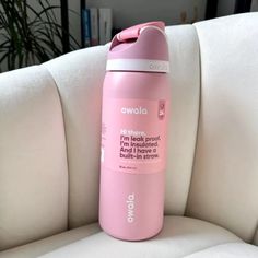 a pink water bottle sitting on top of a white couch