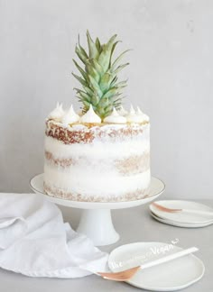 a pineapple on top of a frosted cake next to plates and napkins