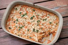 a casserole dish with meat and vegetables in it on a wooden table next to utensils