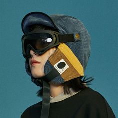 a person wearing a hat and goggles on top of their head with a blue background