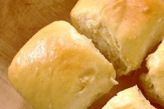 four rolls sitting on top of a wooden cutting board