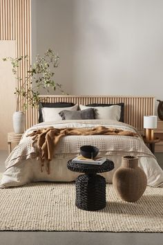 a large bed sitting next to a table with two vases on top of it