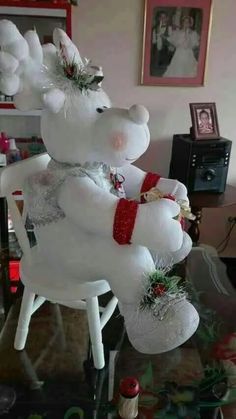 a white teddy bear sitting on top of a chair with christmas decorations around its legs