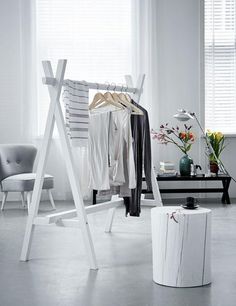 a white clothes rack sitting on top of a floor next to a chair and table