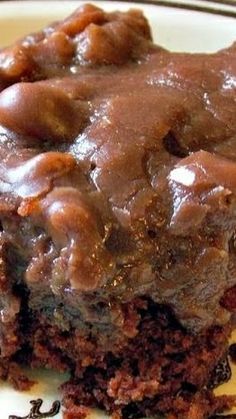 a close up of a piece of cake on a plate with chocolate frosting and nuts