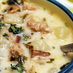 a bowl of soup with meat, cheese and spinach in it next to a spoon