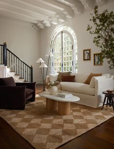 a living room filled with furniture and a large window next to a stair case in front of it