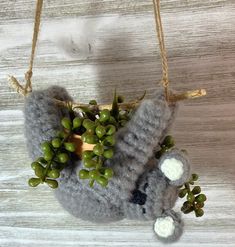 a stuffed animal hanging from a string with some green berries in it's mouth