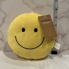 a yellow smiley face stuffed animal with a measuring tape on it's back end