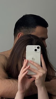 a man and woman hugging each other while looking at their cell phones in front of them