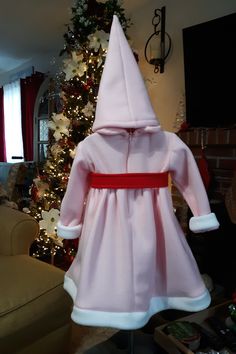 a baby's pink and white coat is on display in front of a christmas tree