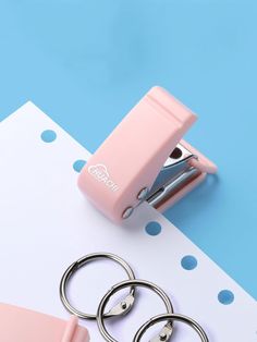 a pair of pink scissors and some metal rings on a blue and white background with polka dots