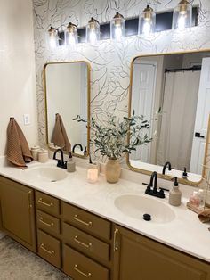 a bathroom with two sinks, mirrors and lights on the wall above them is shown