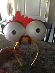 a close up of a person holding a fake chicken head on top of a table