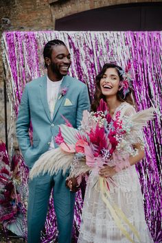 a man and woman standing next to each other in front of some purple tinsel