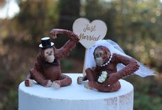 two monkey figurines sitting on top of a white cake with a sign that says just married