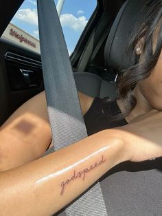 a woman with a tattoo on her arm sitting in a car