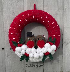 two knitted owls sitting on top of a wreath