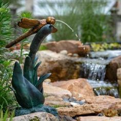 a statue of a bird drinking water out of a faucet in a garden