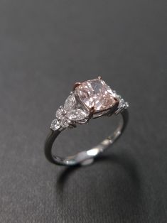 an engagement ring with three diamonds on top and one diamond in the middle, sitting on a black surface