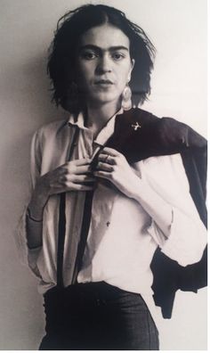 black and white photograph of a woman wearing a shirt, tie and jacket with her hands on her hips