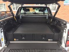 the back end of a white truck with its trunk open and two large black drawers