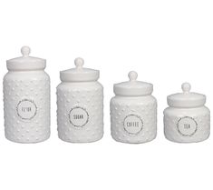 three white ceramic canisters with labels on them