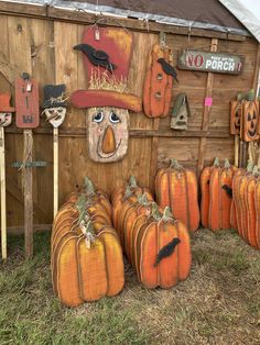 pumpkins are arranged in front of a wooden wall with scarecrow heads on them