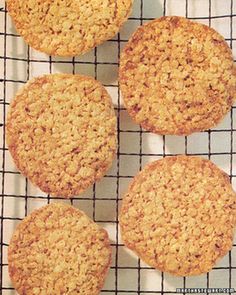 four oatmeal cookies sitting on top of a cooling rack next to each other