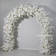 white flowers are arranged in an arch on the floor