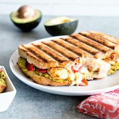 a sandwich on a plate with avocado and salsa in the bowl next to it