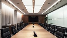 an empty conference room is shown with black leather chairs and wooden tables in front of a projection screen