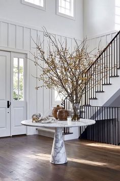 a table that has some flowers on it in the middle of a room with stairs