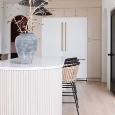 a large vase sitting on top of a kitchen counter next to a bar with stools