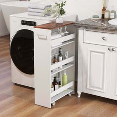 a washer and dryer in a bathroom with white cabinets, marble counter tops and wood flooring