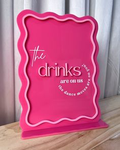 a pink sign that says the drinks are on us