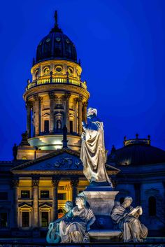 a statue in front of a building with a dome on it's roof at night