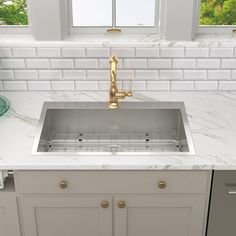 a white kitchen with marble counter tops and gold faucet, undermount sink