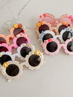 two pairs of sunglasses with flower decorations on them sitting next to each other in front of a marble surface