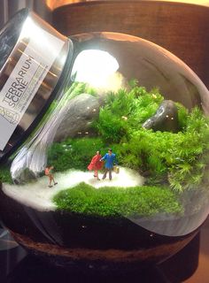 a glass bowl filled with moss and miniature people