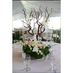 a centerpiece with flowers and branches on a table