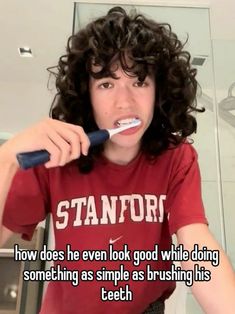 a girl brushing her teeth with an electric toothbrush in front of the camera text reads, how does he even look good while doing something as simple as brushing his teeth