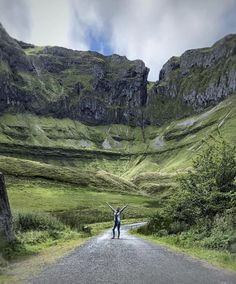 a person standing on the side of a road with their arms in the air