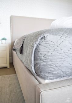 a white bed with an upholstered headboard and pillows on top of it