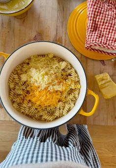 a pot filled with pasta and cheese sitting on top of a wooden table next to other dishes