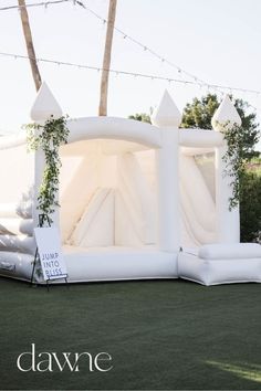 an inflatable tent set up with pillows and greenery on the grass at a wedding