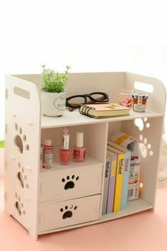 a white shelf with some books and glasses on it's top, next to a potted plant