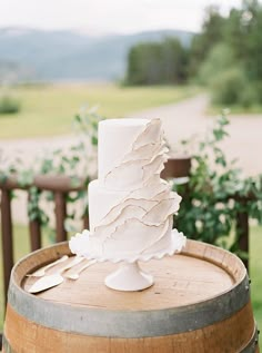 a white wedding cake sitting on top of a barrel